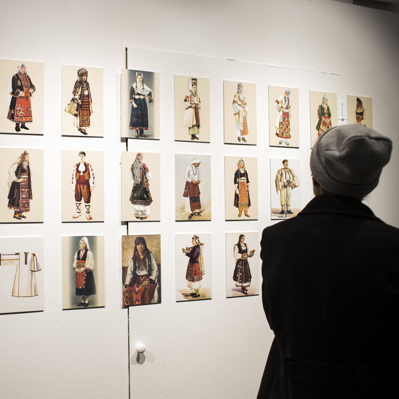 Fotografia przedstawia, zwiedzającego wystawę, który ogląda wizerunki bułgarskich strojów tradycyjnych, przedstawionych na planszach.