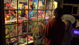 Zdjęcie kolorowe dwójki dzieci stojącej przed podświetlaną witryną z kolekcją zabawek.