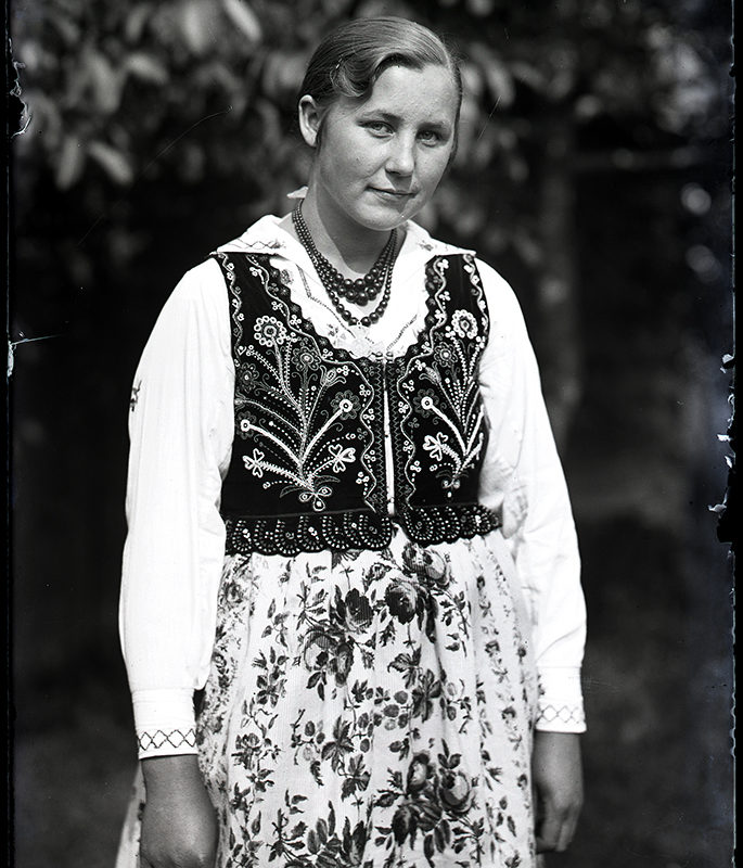 Strój. Kobieta w stroju łąckim_Arch. PME N.4146_4. Kobieta w stroju łąckim ubrana w spódnicę w kwiaty, haftowaną lnianą, białą koszulę, bogato haftowany gorset oraz korale