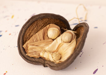 Dwie postacie ludzkie z dzieckiem umieszczone w owocu figowca. Postacie wykonane z liści kukurydzy