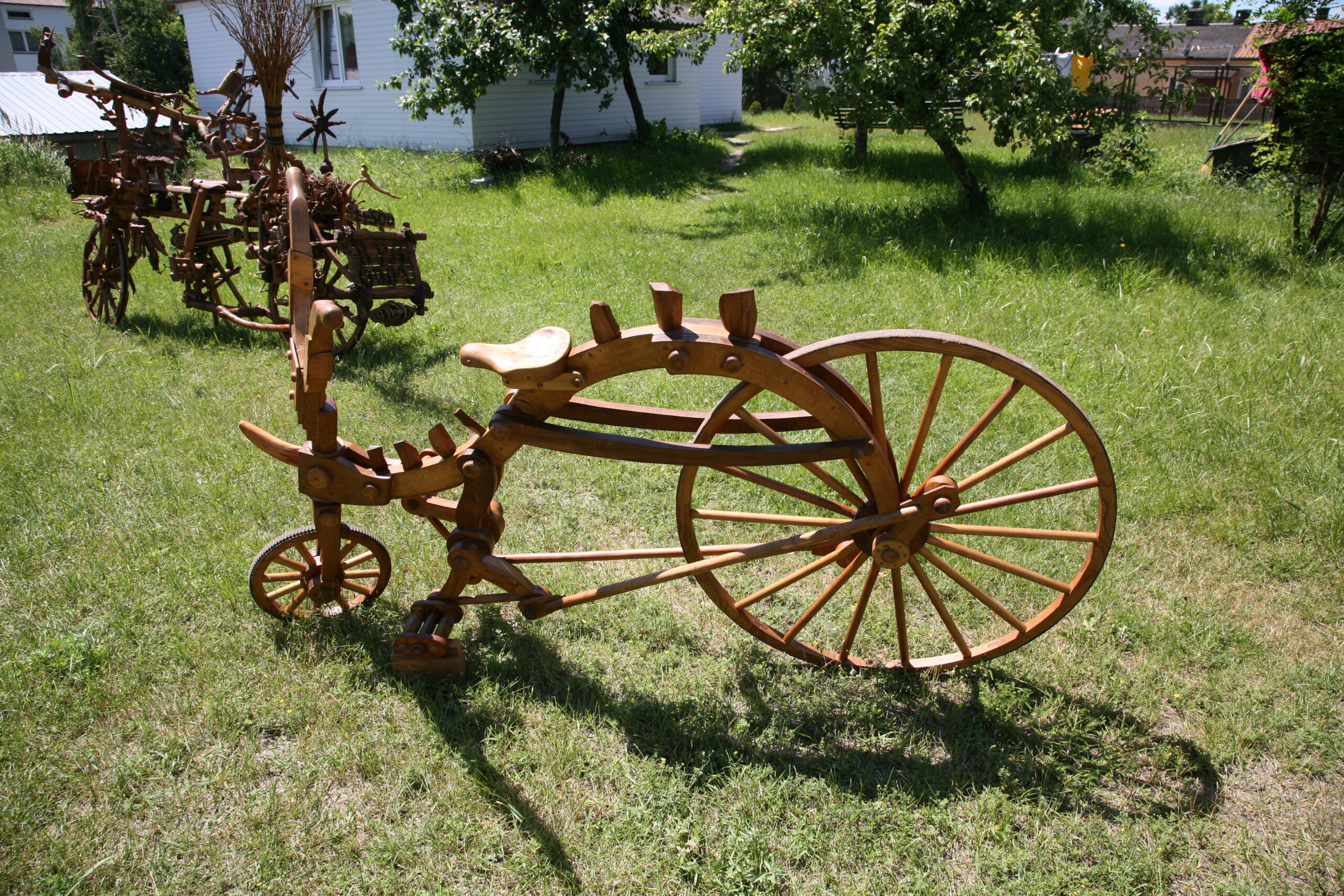 Rower w całości wykonany z drewna, stojący na trawniku.