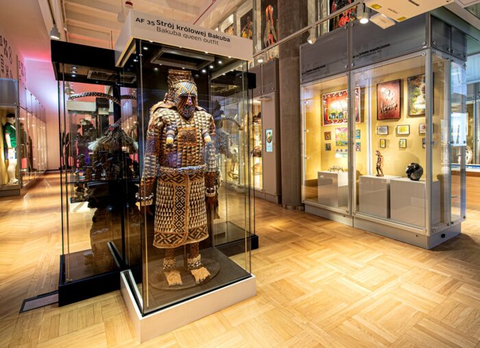 Zdjęcie przedstawia galerie wystawy afrykańskiej. Strój królowej Bakuba w szklanej gablocie. 