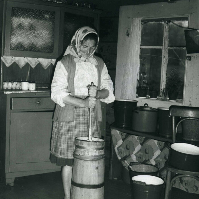 Kobieta ubija masło w tradycyjny sposób. Zdjęcie czarno białe. 