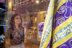 Kobieta patrzy na tradycyjny afrykański strój, który znjaduje się w szklanej gablocie na wystawie.